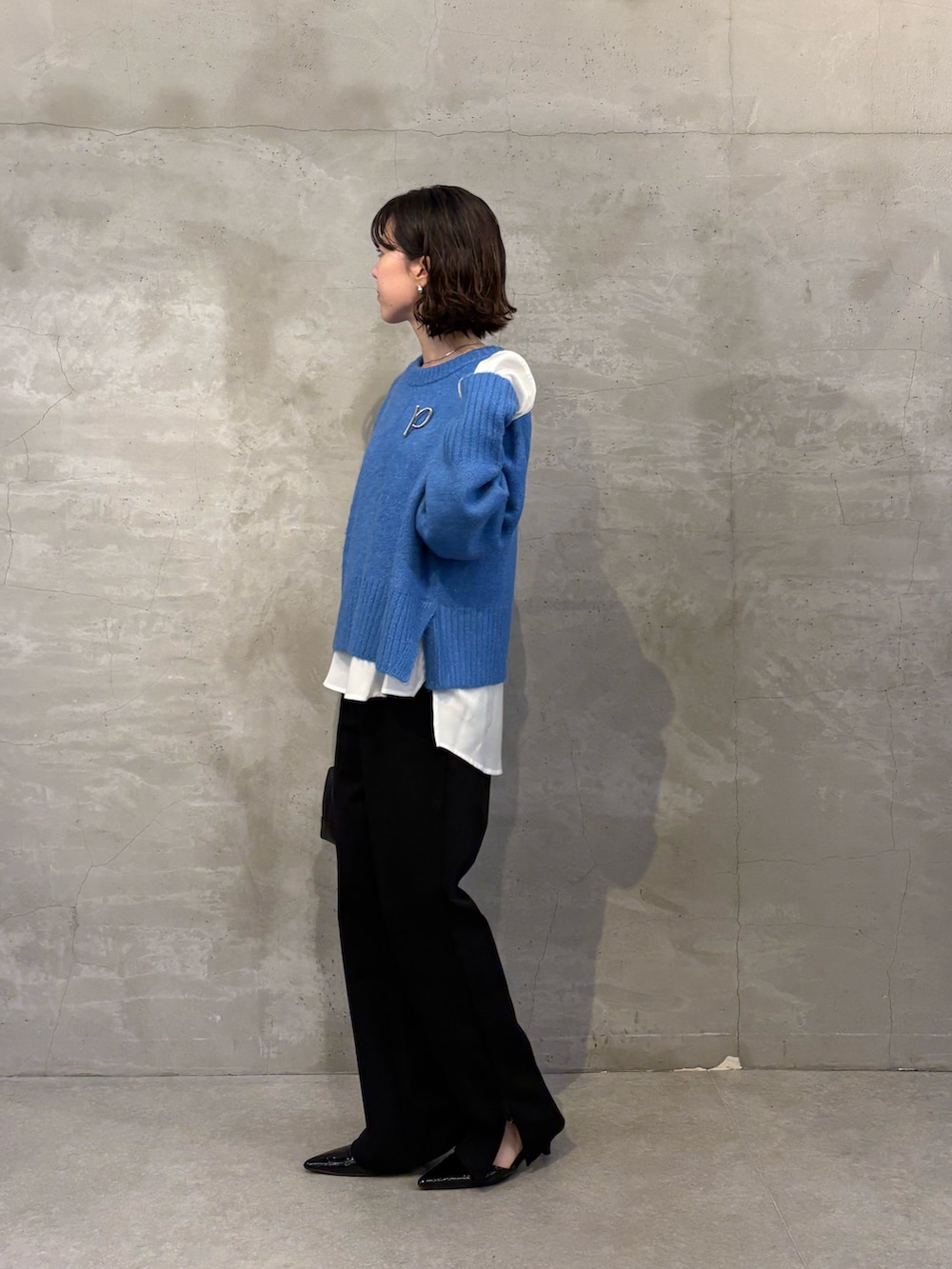 ブルー系のニット/セーター、ホワイト系のシャツ/ブラウス、ブラック系のその他パンツを着用したレディースの秋コーディネートの2枚目の写真