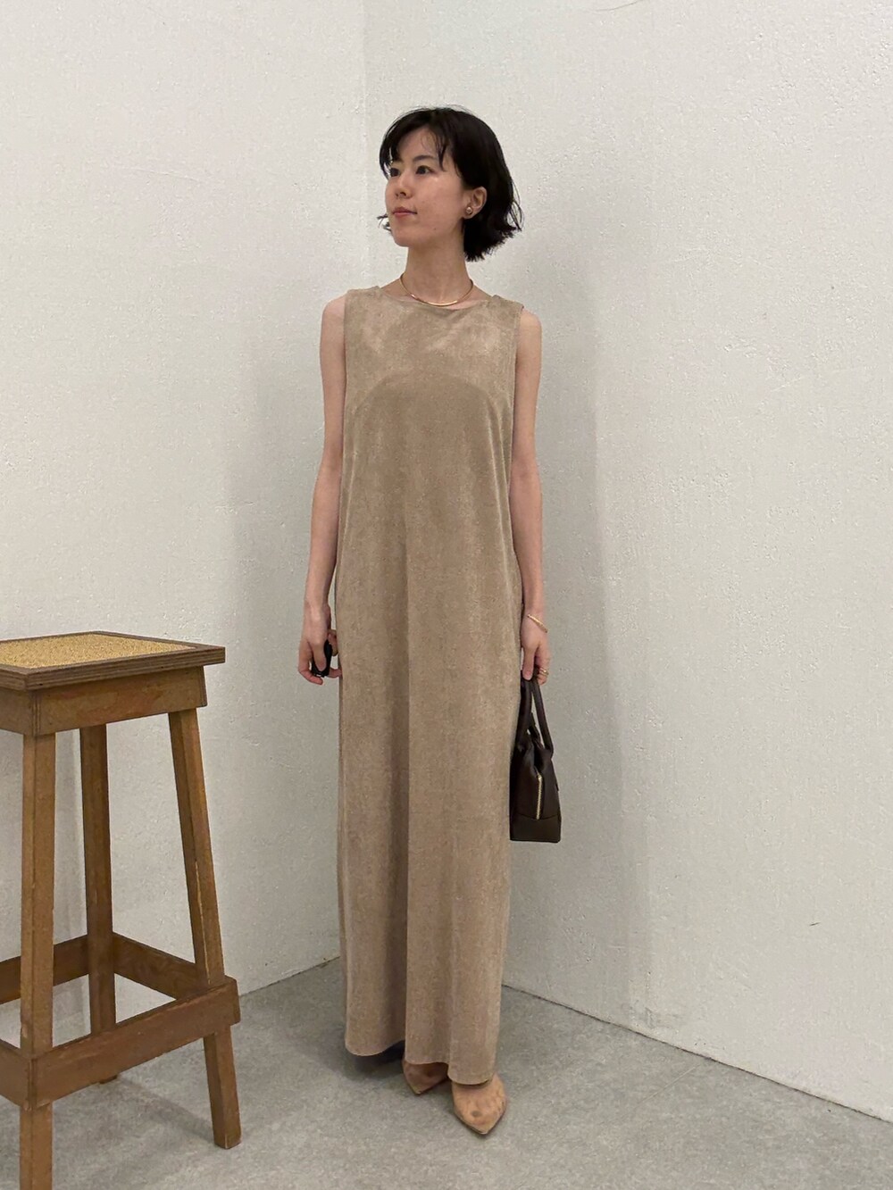 ベージュ系のワンピース、ブラウン系のショルダーバッグ、ゴールド系のネックレスを着用したレディースの夏コーディネートの3枚目の写真