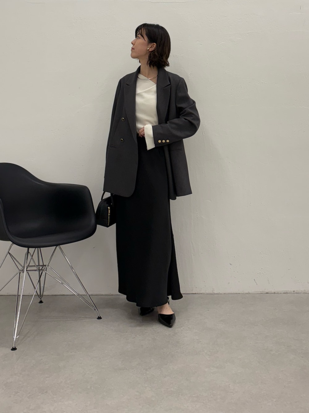 ブラック系のスカート、ブラック系のパンプス、ブラック系のボストンバッグを着用したレディースの秋コーディネートの5枚目の写真