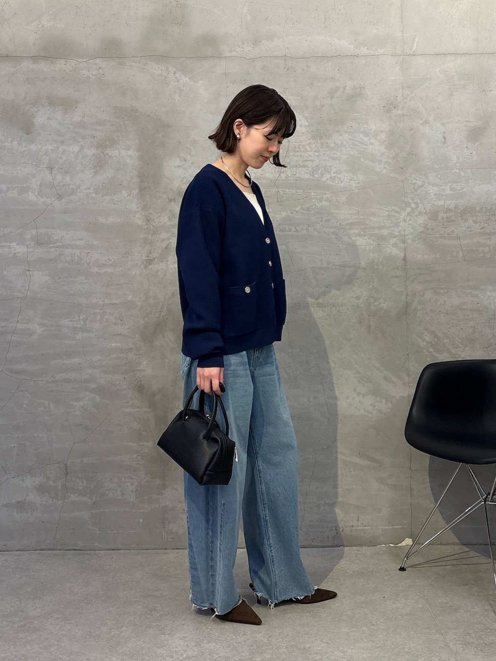 ブルー系のデニムパンツ、ブラック系のボストンバッグ、ブルー系のカーディガン/ボレロを着用したレディースの冬コーディネートの2枚目の写真