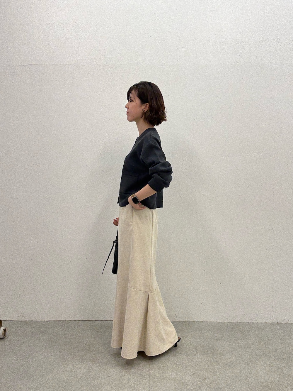 グレー系のカーディガン/ボレロ、ホワイト系のスカート、ブラック系のトートバッグを着用したレディースの夏コーディネートの2枚目の写真