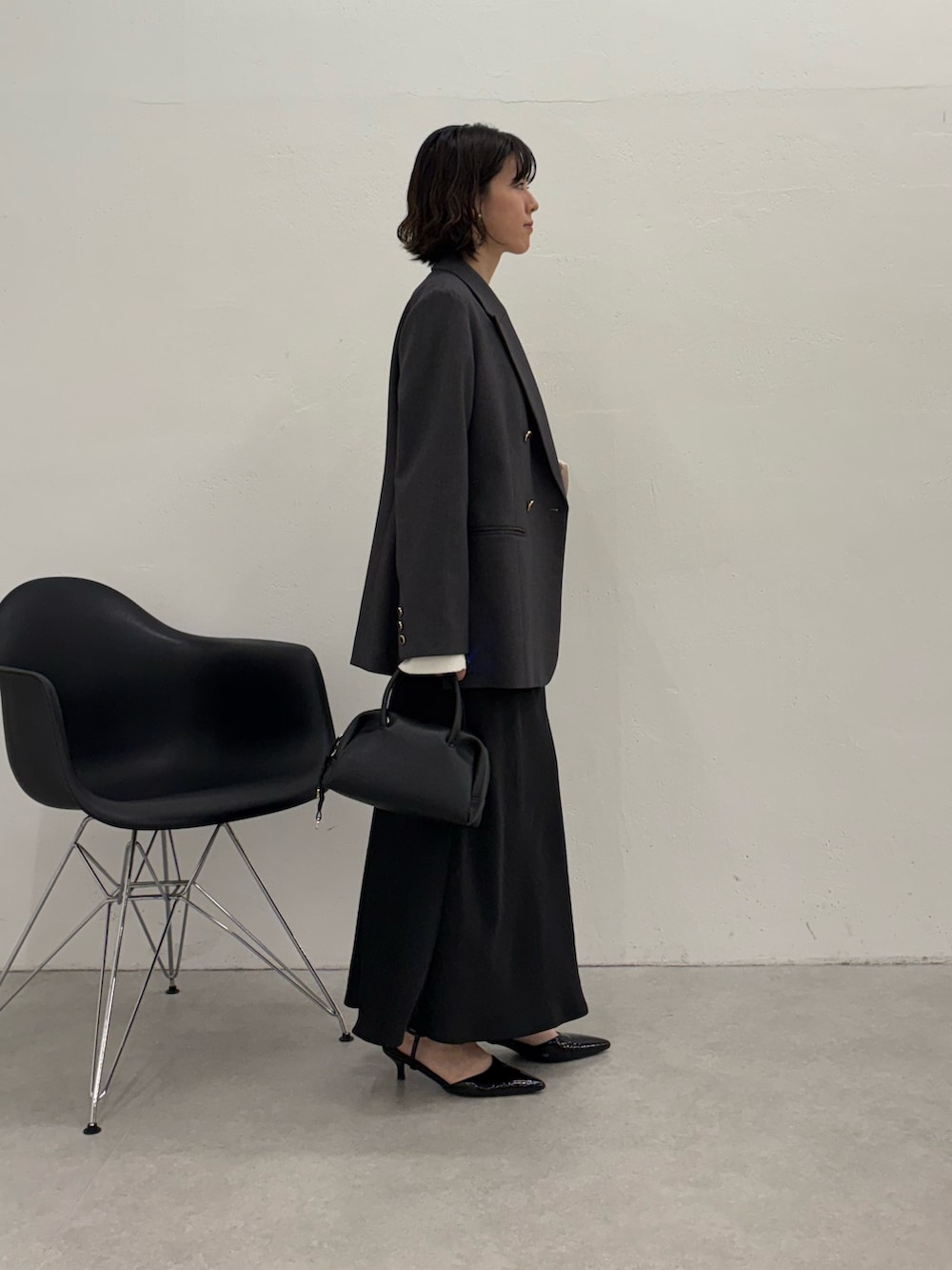 ブラック系のスカート、ブラック系のパンプス、ブラック系のボストンバッグを着用したレディースの秋コーディネートの4枚目の写真