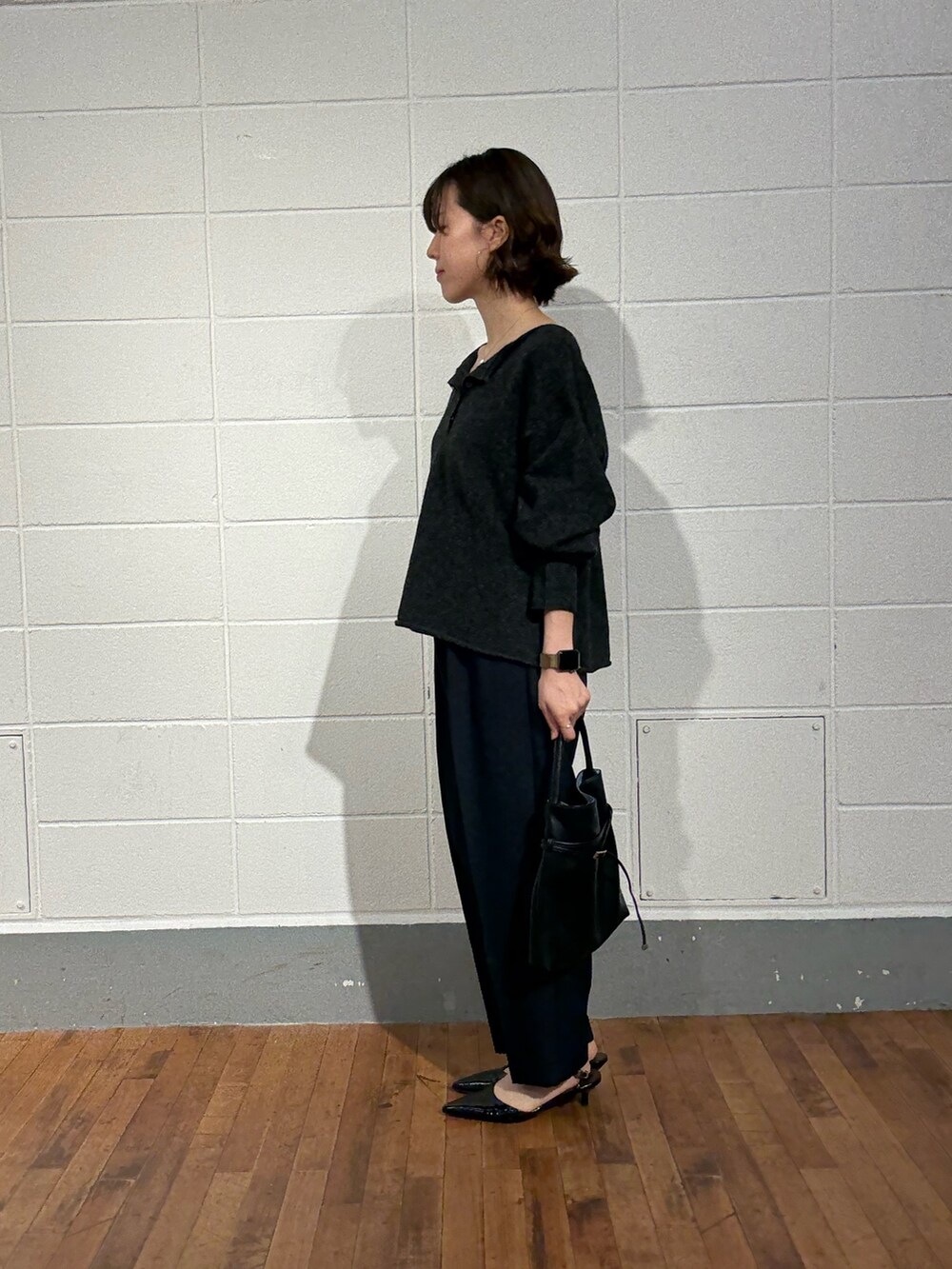 グレー系のニット/セーター、ブルー系のその他パンツ、ブラック系のトートバッグを着用したレディースの秋コーディネートの2枚目の写真