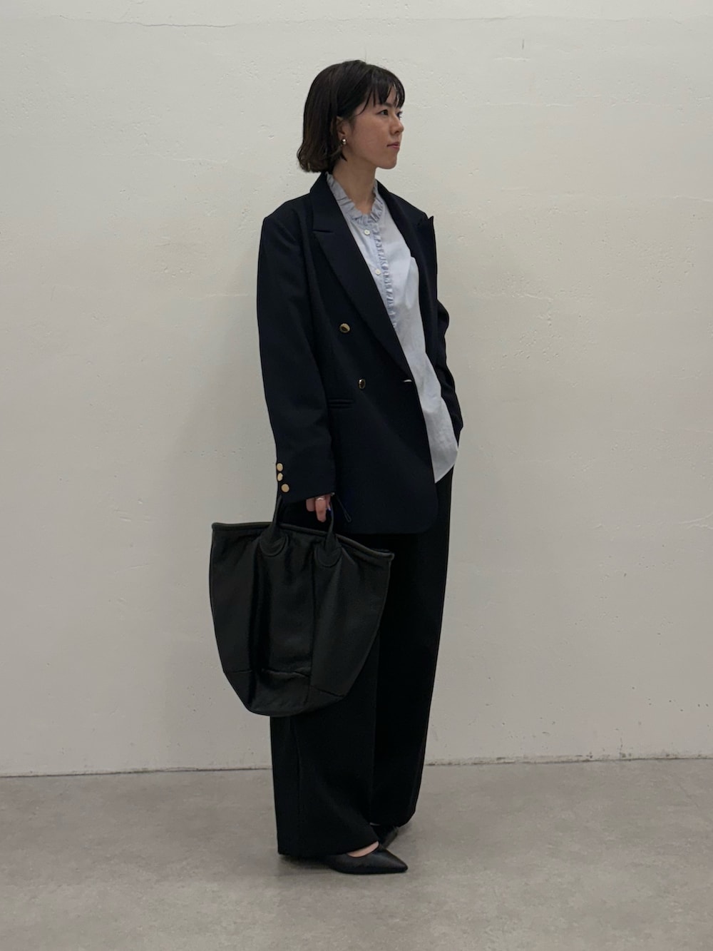 ブルー系のスラックス、ブルー系のテーラードジャケット、ブラック系のトートバッグを着用したレディースの秋コーディネートの2枚目の写真