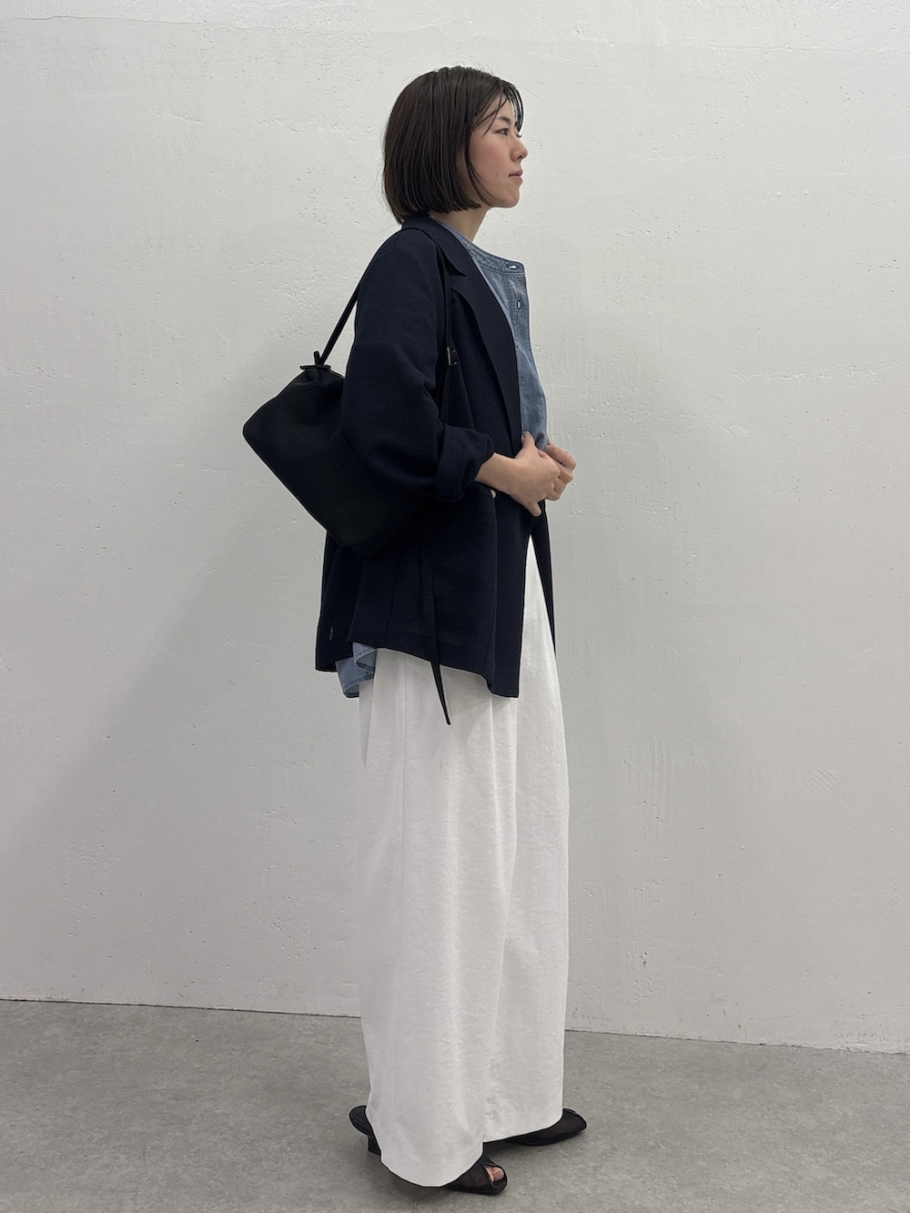 ホワイト系のスラックス、ブルー系のテーラードジャケット、ブラック系のサンダルを着用したレディースの春コーディネートの4枚目の写真