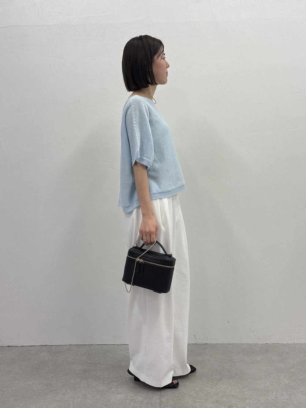 ホワイト系のスラックス、ブラック系のショルダーバッグ、ブラック系のサンダルを着用したレディースの春コーディネートの4枚目の写真