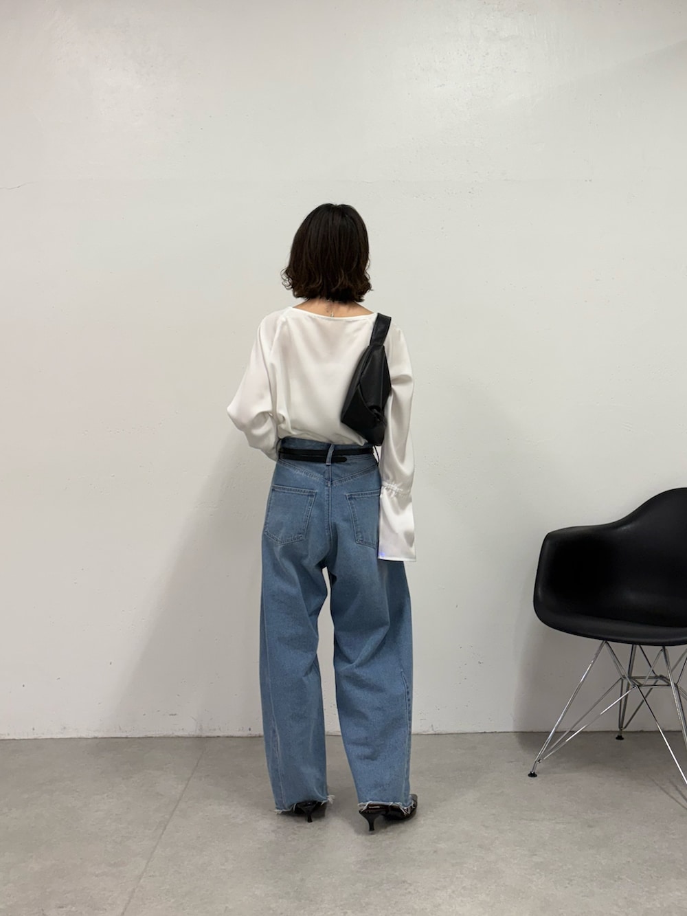 ブルー系のデニムパンツ、ブラック系のパンプス、ブラック系のショルダーバッグを着用したレディースの秋コーディネートの3枚目の写真