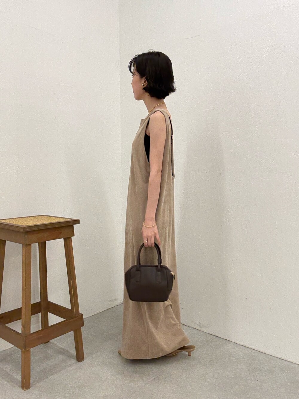 ベージュ系のワンピース、ブラウン系のショルダーバッグ、ゴールド系のネックレスを着用したレディースの夏コーディネートの2枚目の写真