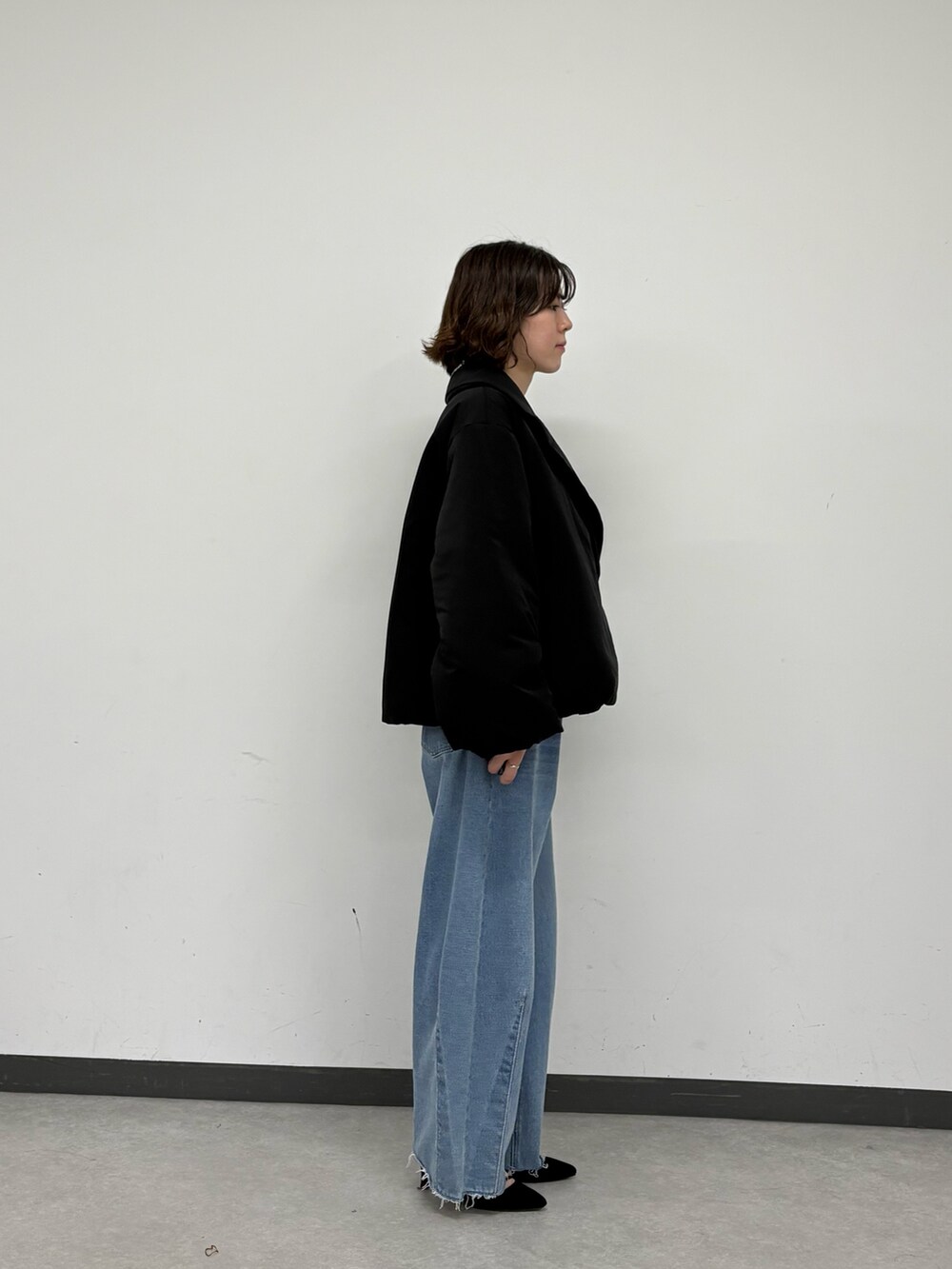 ブラック系のその他アウター、ブルー系のデニムパンツ、ホワイト系のニット/セーターを着用したレディースの秋コーディネートの2枚目の写真