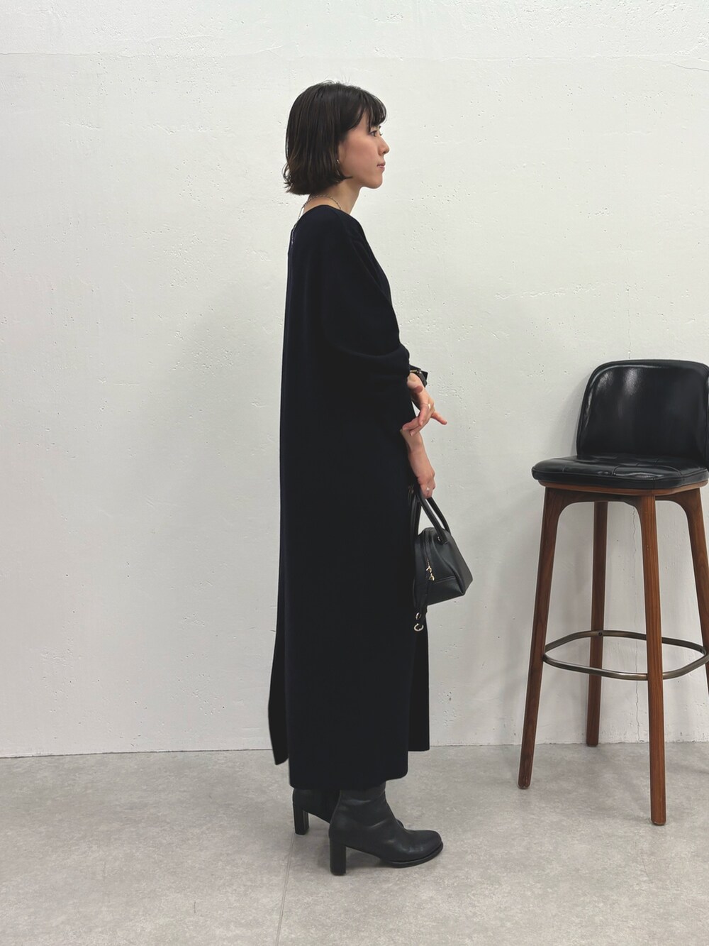ブルー系のワンピース、ブラック系のブーツ、ブラック系のボストンバッグを着用したレディースの秋コーディネートの2枚目の写真