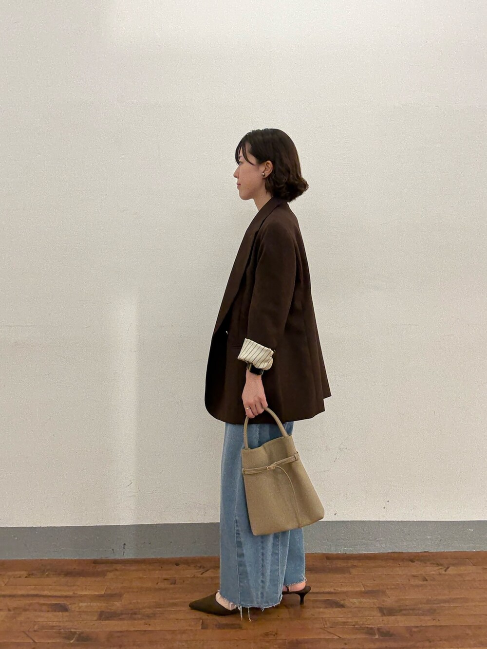 ベージュ系のトートバッグ、ブルー系のデニムパンツ、ブラウン系のパンプスを着用したレディースの秋コーディネートの2枚目の写真