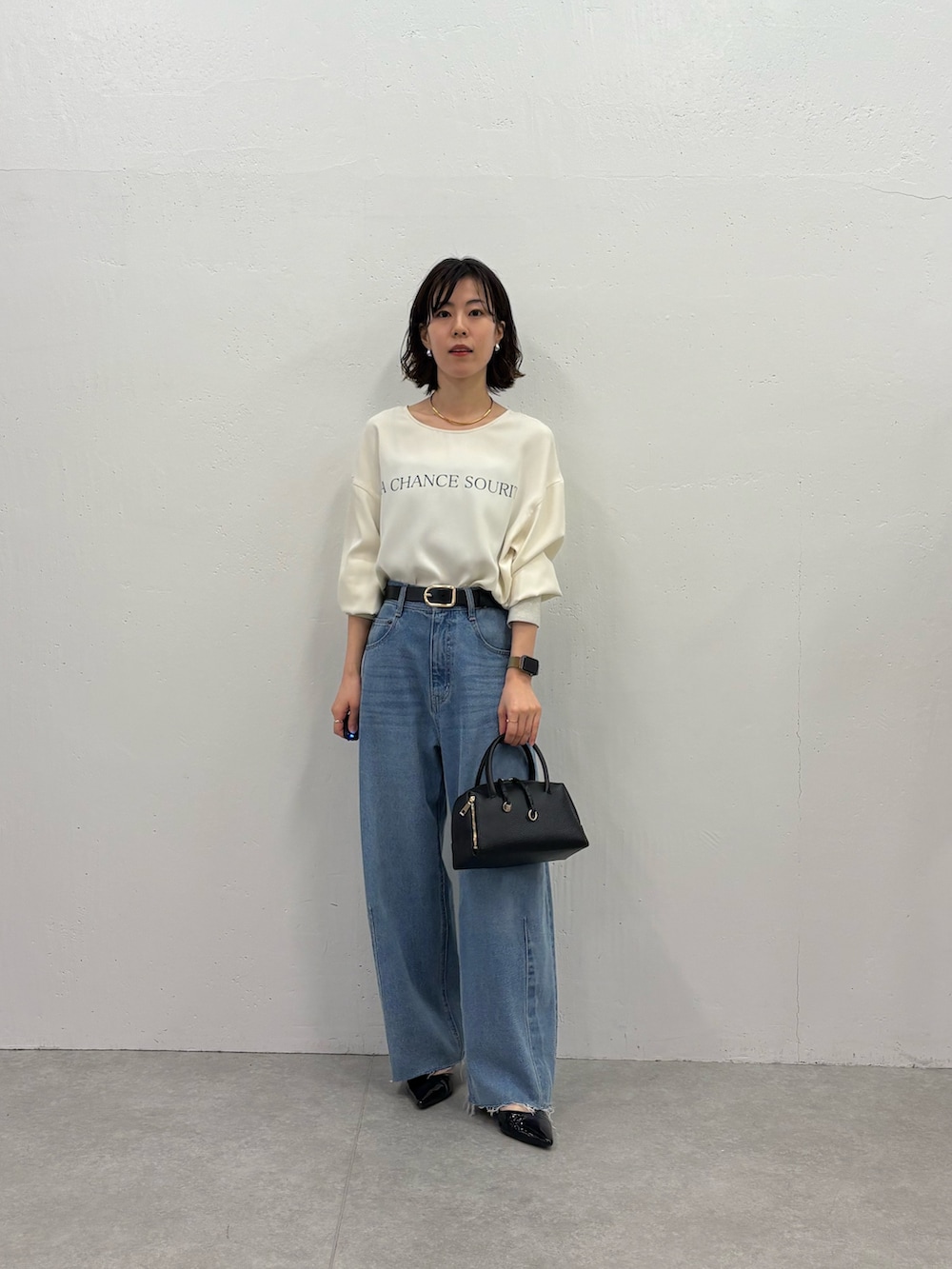 ブルー系のデニムパンツ、ブラック系のパンプス、ブラック系のボストンバッグを着用したレディースの秋コーディネートの4枚目の写真