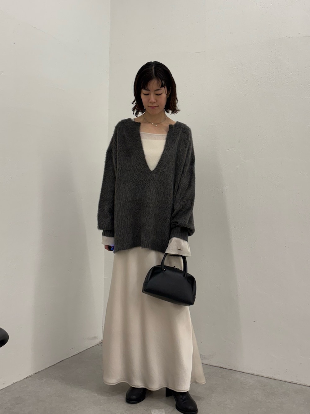 ホワイト系のスカート、ブラック系のボストンバッグ、ブラック系のブーツを着用したレディースの秋コーディネートの2枚目の写真