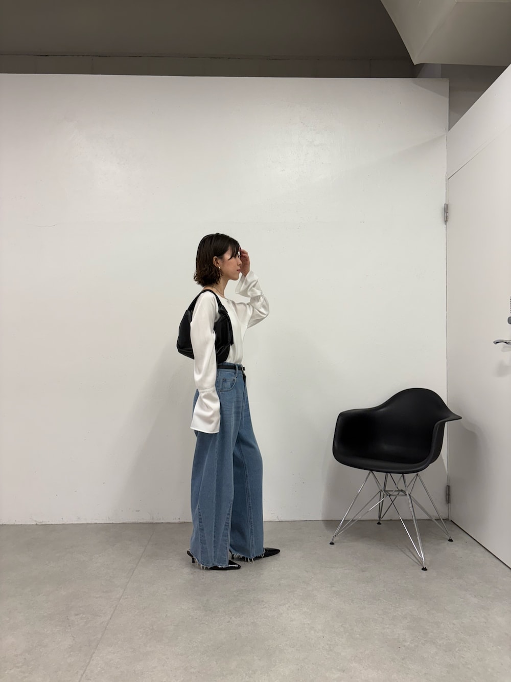 ブルー系のデニムパンツ、ブラック系のパンプス、ブラック系のショルダーバッグを着用したレディースの秋コーディネートの4枚目の写真