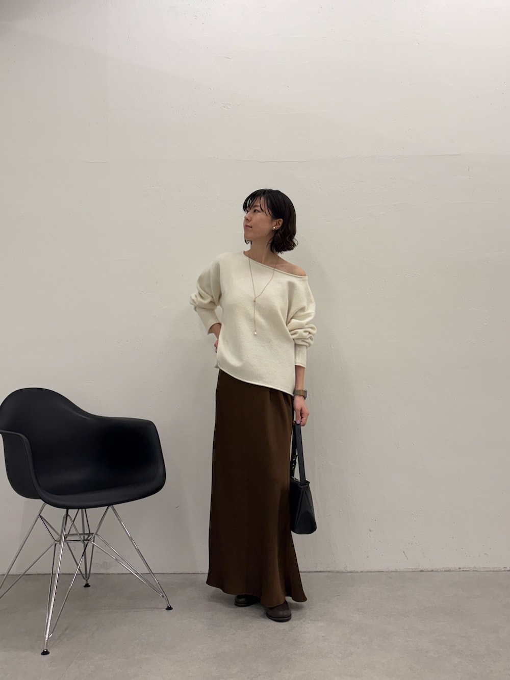 ホワイト系のニット/セーター、ブラック系のショルダーバッグ、ブラウン系のスカートを着用したレディースの秋コーディネートの4枚目の写真