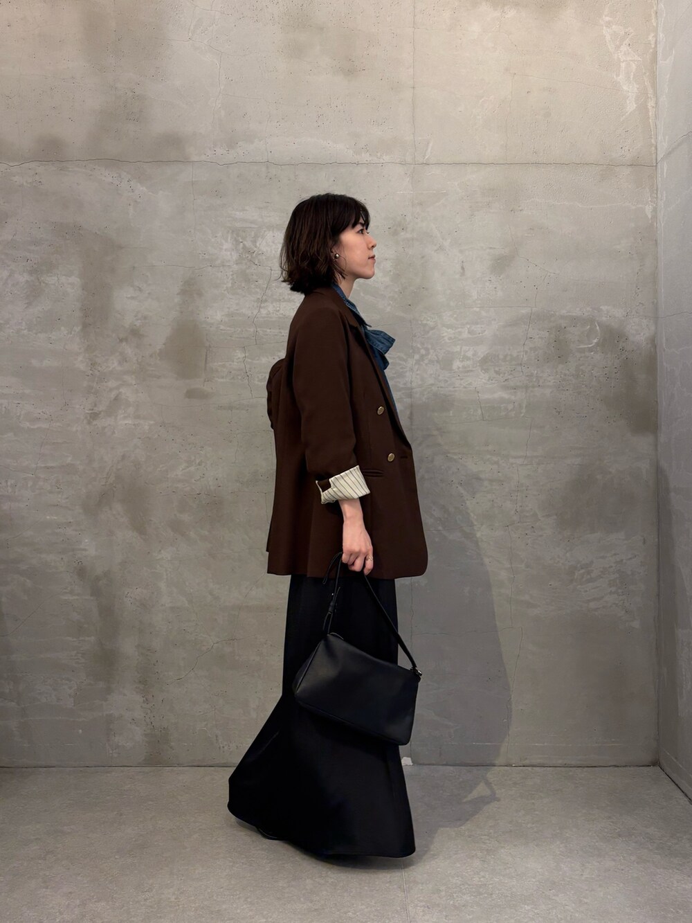 ブラウン系のテーラードジャケット、ブラック系のスカート、ブラック系のブーツを着用したレディースの秋コーディネートの3枚目の写真