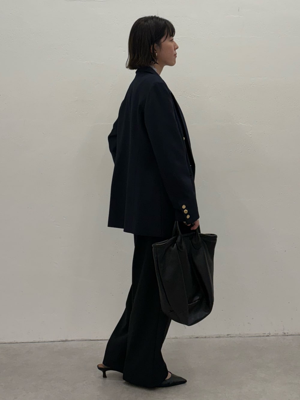 ブルー系のスラックス、ブルー系のテーラードジャケット、ブラック系のトートバッグを着用したレディースの秋コーディネートの3枚目の写真