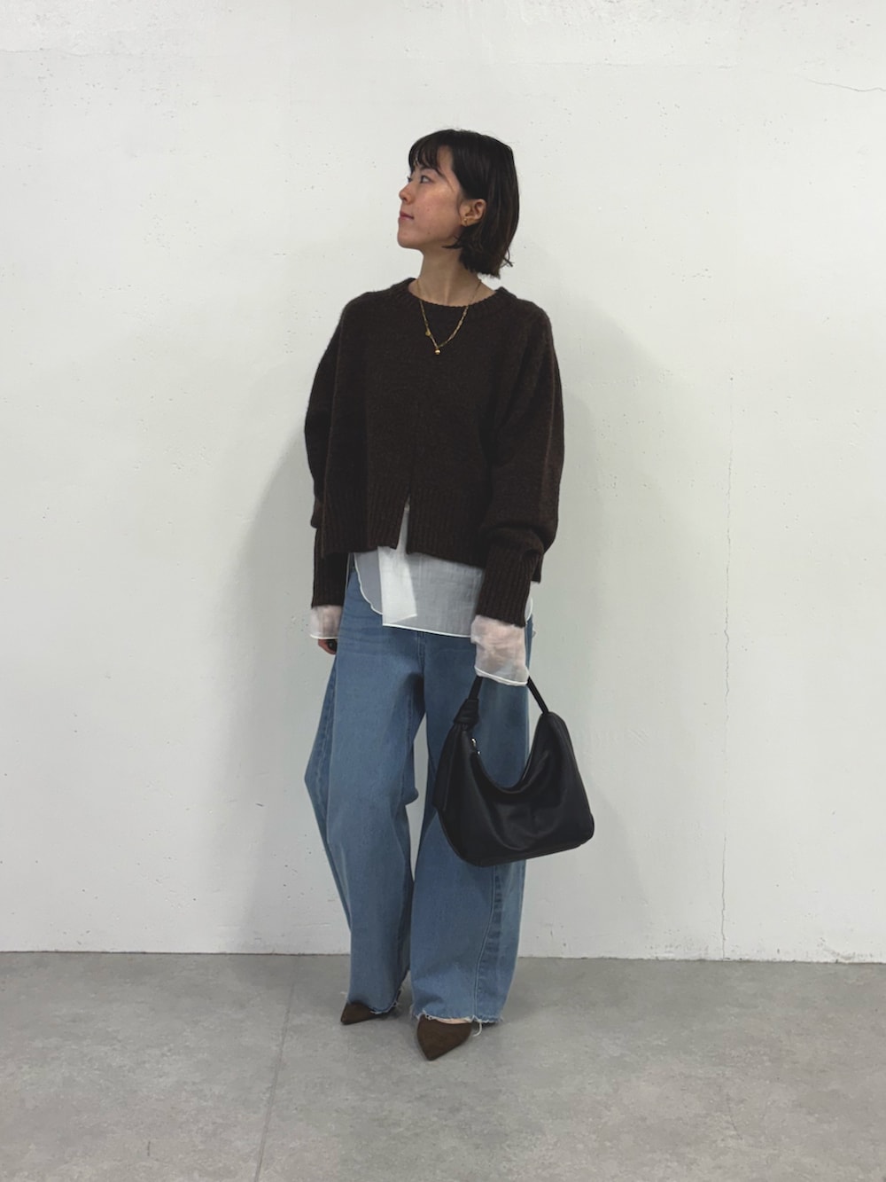 グレー系のニット/セーター、ブルー系のデニムパンツ、ホワイト系のTシャツ/カットソーを着用したレディースの秋コーディネートの4枚目の写真