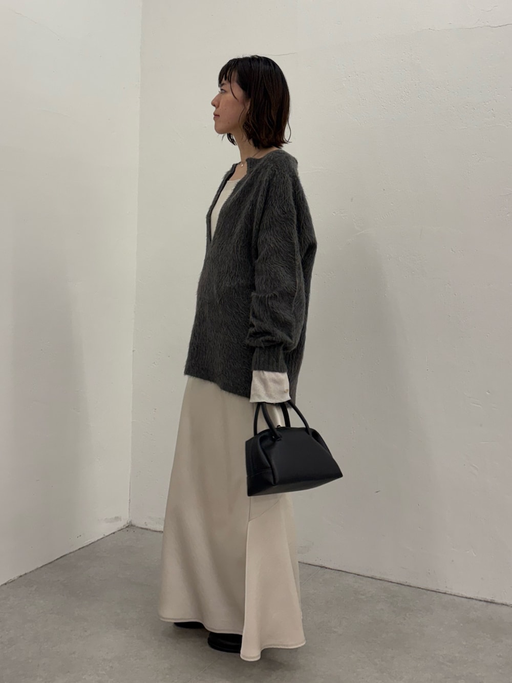 ホワイト系のスカート、ブラック系のボストンバッグ、ブラック系のブーツを着用したレディースの秋コーディネートの3枚目の写真