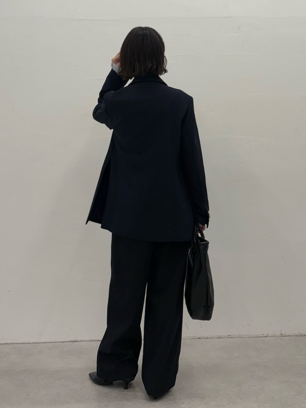 ブルー系のスラックス、ブルー系のテーラードジャケット、ブラック系のトートバッグを着用したレディースの秋コーディネートの4枚目の写真