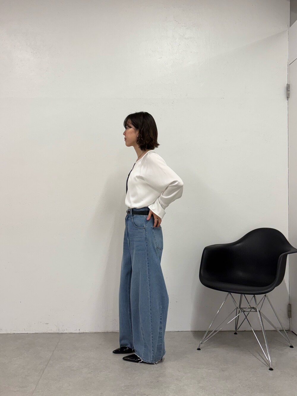 ブルー系のデニムパンツ、ブラック系のパンプス、ブラック系のショルダーバッグを着用したレディースの秋コーディネートの2枚目の写真