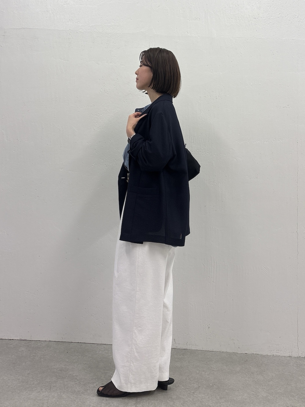 ホワイト系のスラックス、ブルー系のテーラードジャケット、ブラック系のサンダルを着用したレディースの春コーディネートの2枚目の写真