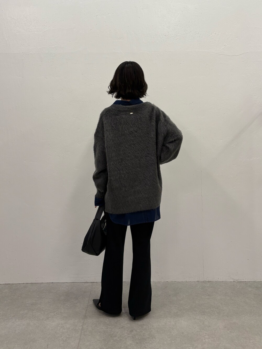 グレー系のニット/セーター、ブルー系のシャツ/ブラウス、ブラック系のパンプスを着用したレディースの秋コーディネートの3枚目の写真