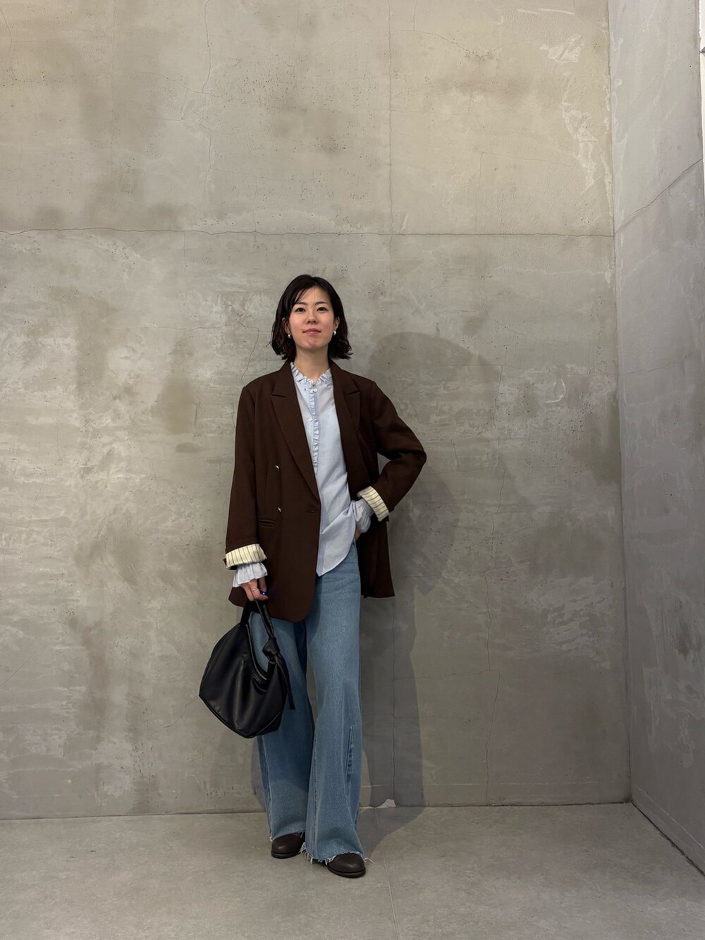 ブルー系のシャツ/ブラウス、ブルー系のデニムパンツ、ブラック系のショルダーバッグを着用したレディースの秋コーディネートの4枚目の写真