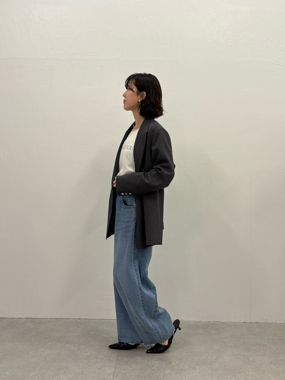 ホワイト系のTシャツ/カットソー、グレー系のテーラードジャケット、ブルー系のデニムパンツを着用したレディースの秋コーディネートの2枚目の写真