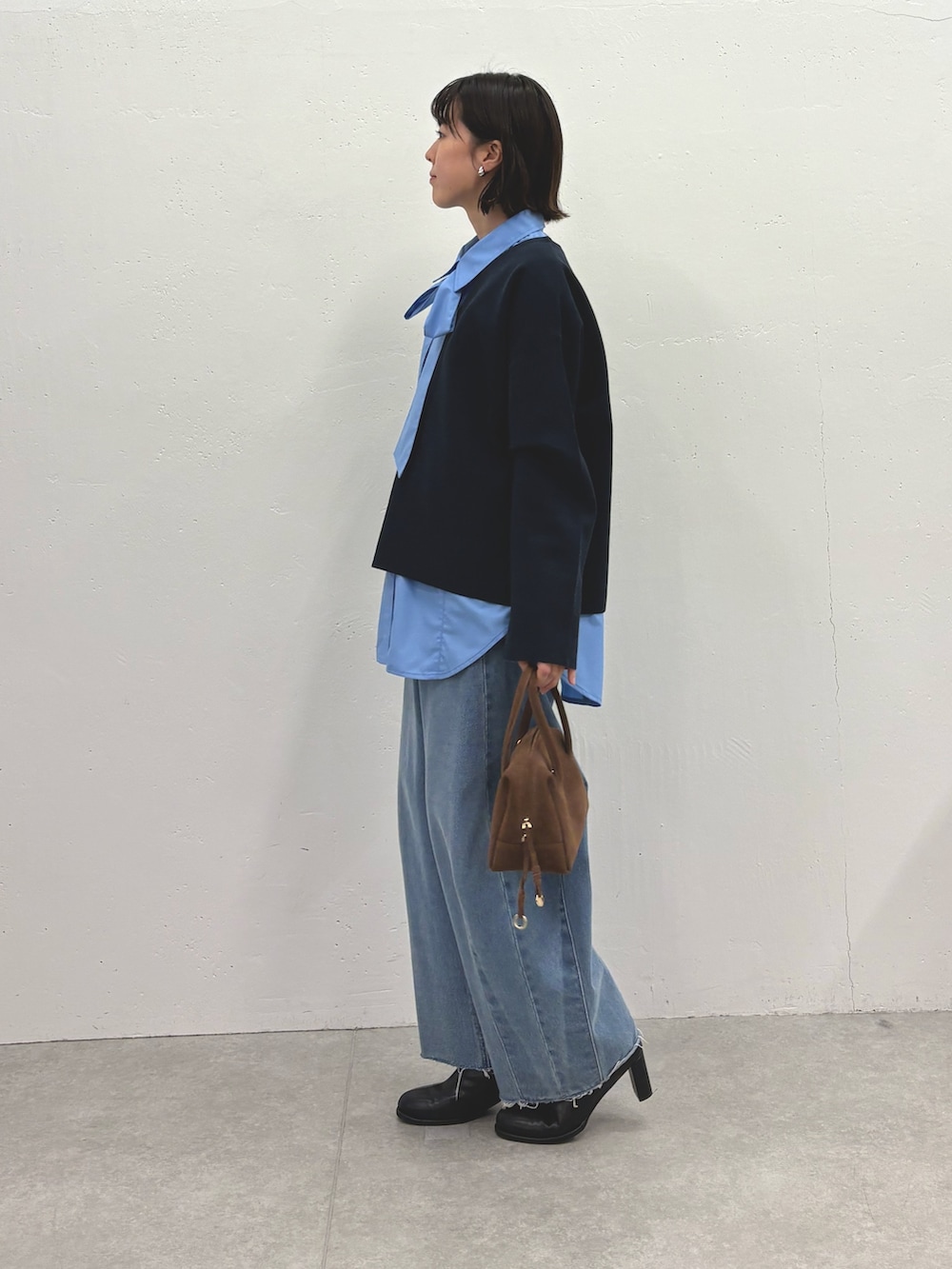 ブラック系のニット/セーター、ブルー系のシャツ/ブラウス、ブルー系のデニムパンツを着用したレディースの秋コーディネートの4枚目の写真