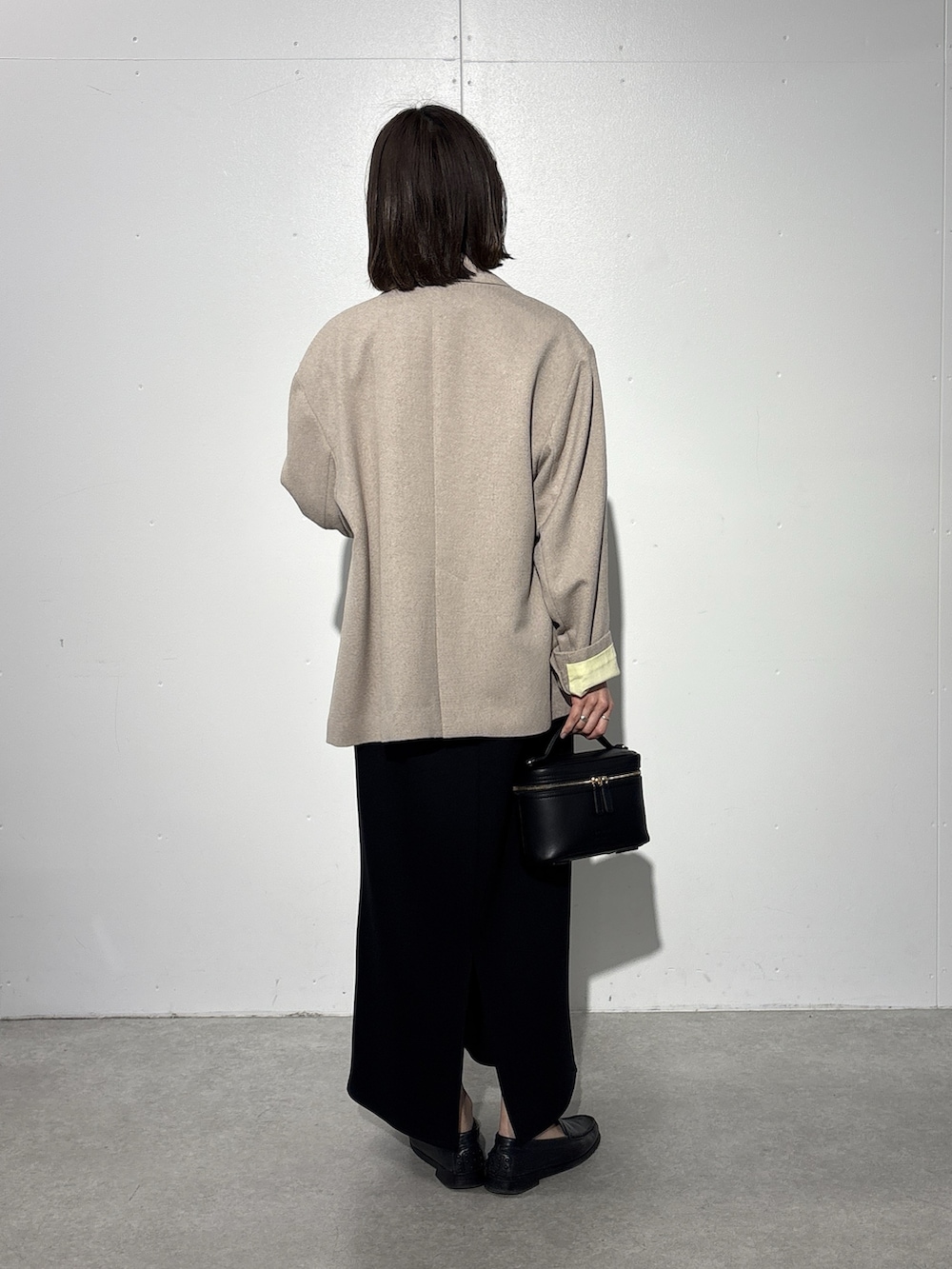 ベージュ系のテーラードジャケット、ブラック系のスカート、ホワイト系のTシャツ/カットソーを着用したレディースの冬コーディネートの3枚目の写真