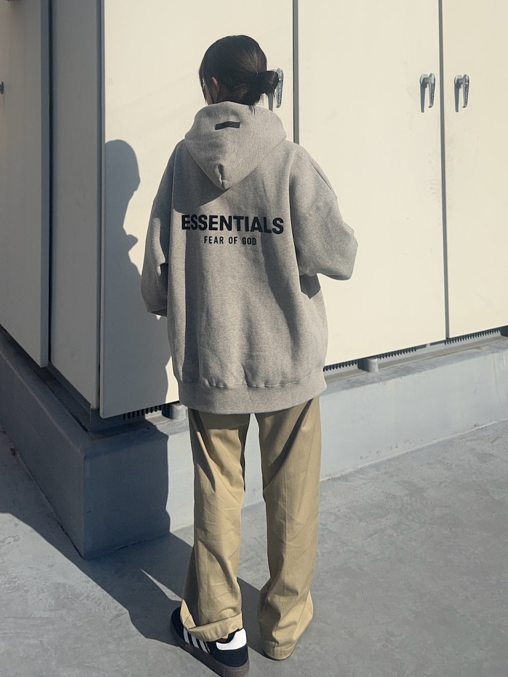 グレー系のパーカー、ベージュ系のチノパンツ、ブラック系のスニーカーを着用したレディースの冬コーディネートの2枚目の写真