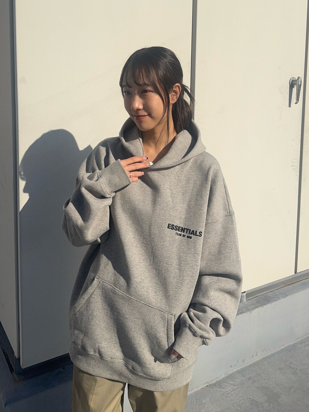 グレー系のパーカー、ベージュ系のチノパンツ、ブラック系のスニーカーを着用したレディースの冬コーディネートの3枚目の写真