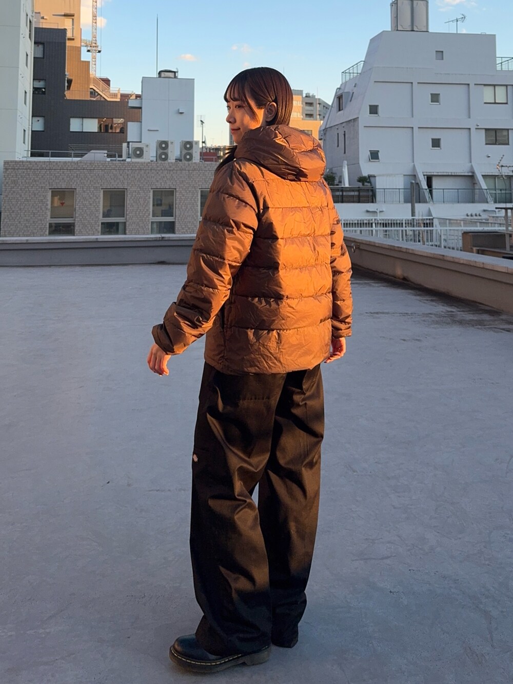 ブラウン系のダウンジャケット/コート、ブラック系のチノパンツ、ブラック系のブーツを着用したレディースの冬コーディネートの2枚目の写真