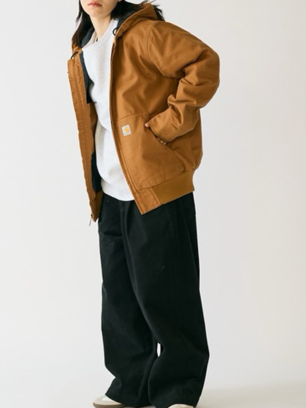 ブラウン系のマウンテンパーカー、ブラック系のスラックス、ホワイト系のスニーカーを着用したレディースの秋コーディネートの2枚目の写真