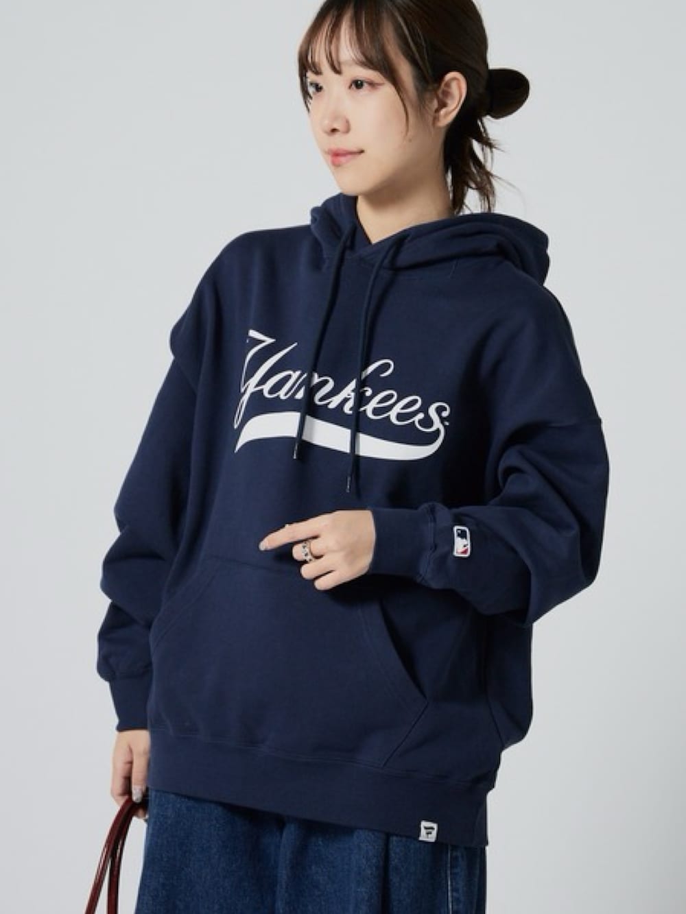 ブルー系のパーカー、ブルー系のデニムパンツ、レッド系のショルダーバッグを着用したレディースの秋コーディネートの2枚目の写真