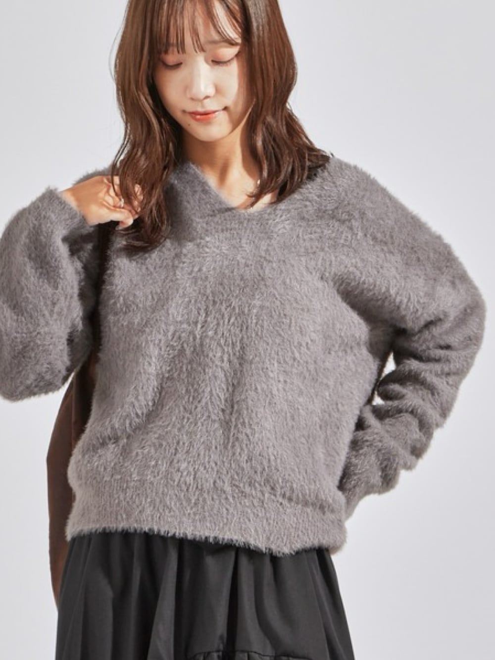 グレー系のニット/セーター、ブラック系のスカート、ブラック系のブーツを着用したレディースの秋コーディネートの2枚目の写真