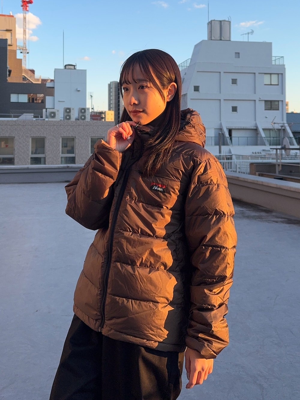 ブラウン系のダウンジャケット/コート、ブラック系のチノパンツ、ブラック系のブーツを着用したレディースの冬コーディネートの3枚目の写真