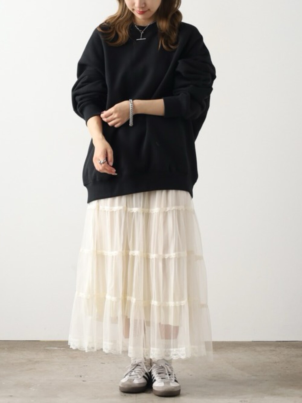 ブラック系のスウェット、ベージュ系のスカート、ホワイト系のスニーカーを着用したレディースの夏コーディネートの2枚目の写真