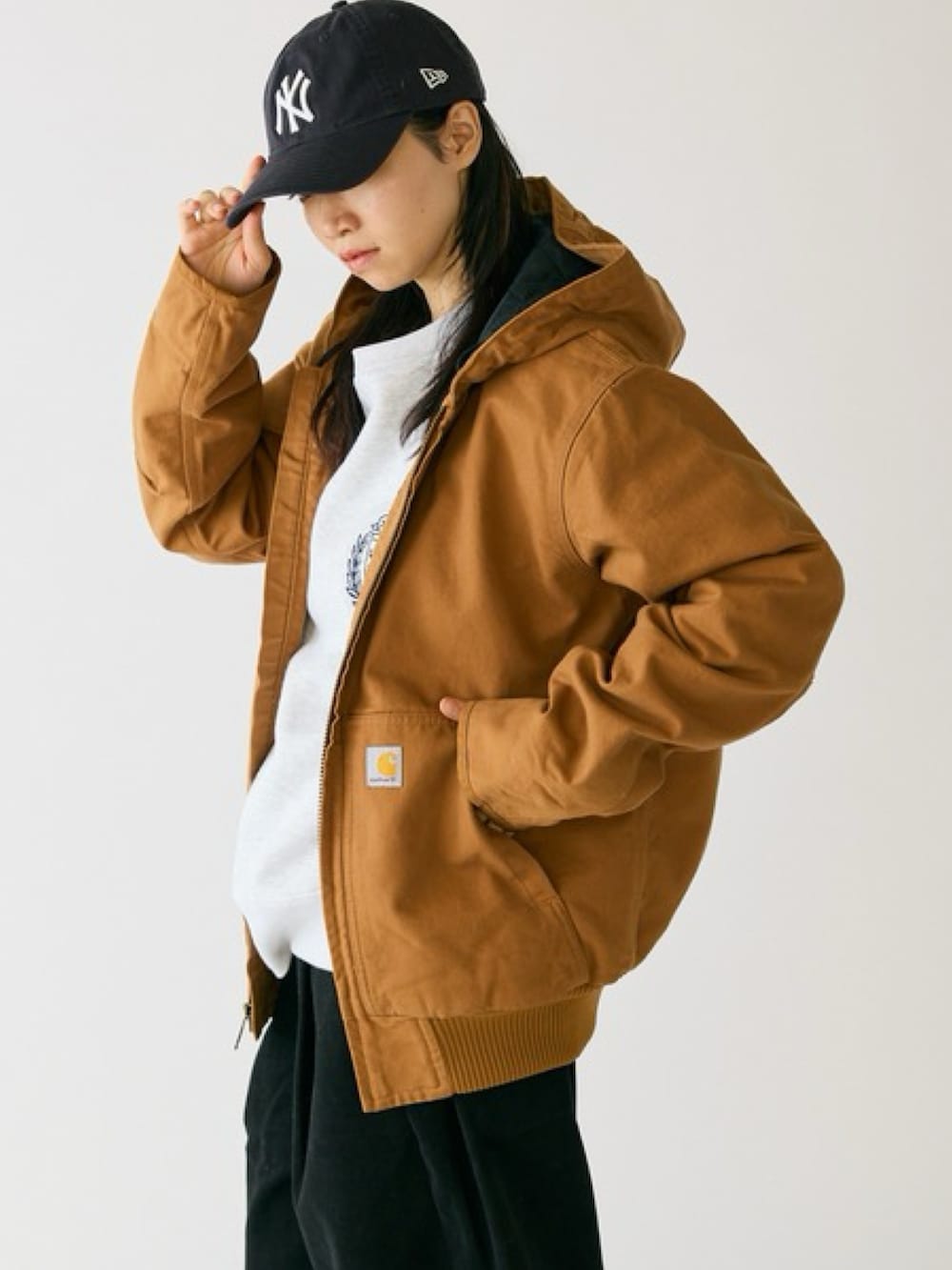 ブラウン系のマウンテンパーカー、ブラック系のスラックス、ホワイト系のスニーカーを着用したレディースの秋コーディネートの3枚目の写真