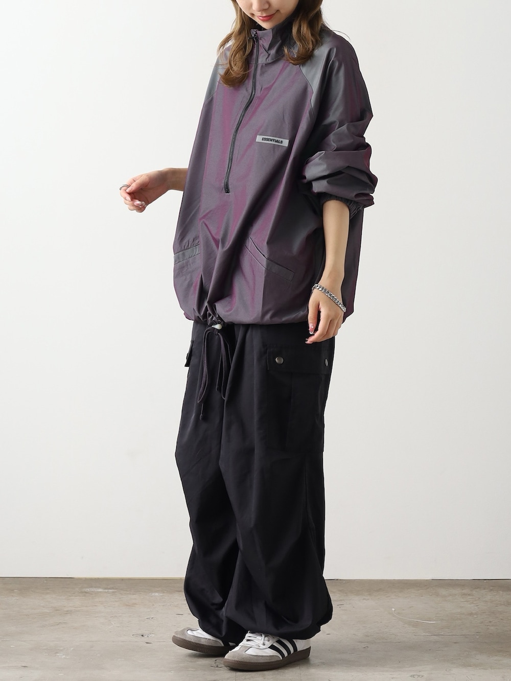 パープル系のブルゾン、ブラック系のカーゴパンツ、ホワイト系のスニーカーを着用したレディースの秋コーディネートの2枚目の写真