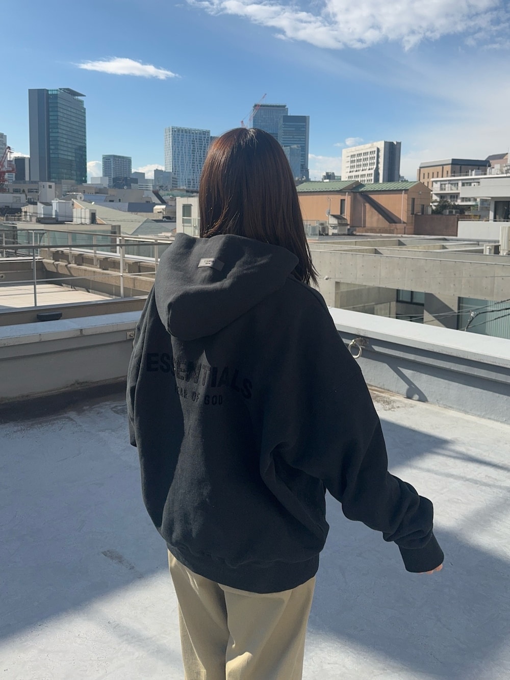 ブラック系のパーカー、ベージュ系のチノパンツ、ブラック系のスニーカーを着用したレディースの冬コーディネートの6枚目の写真