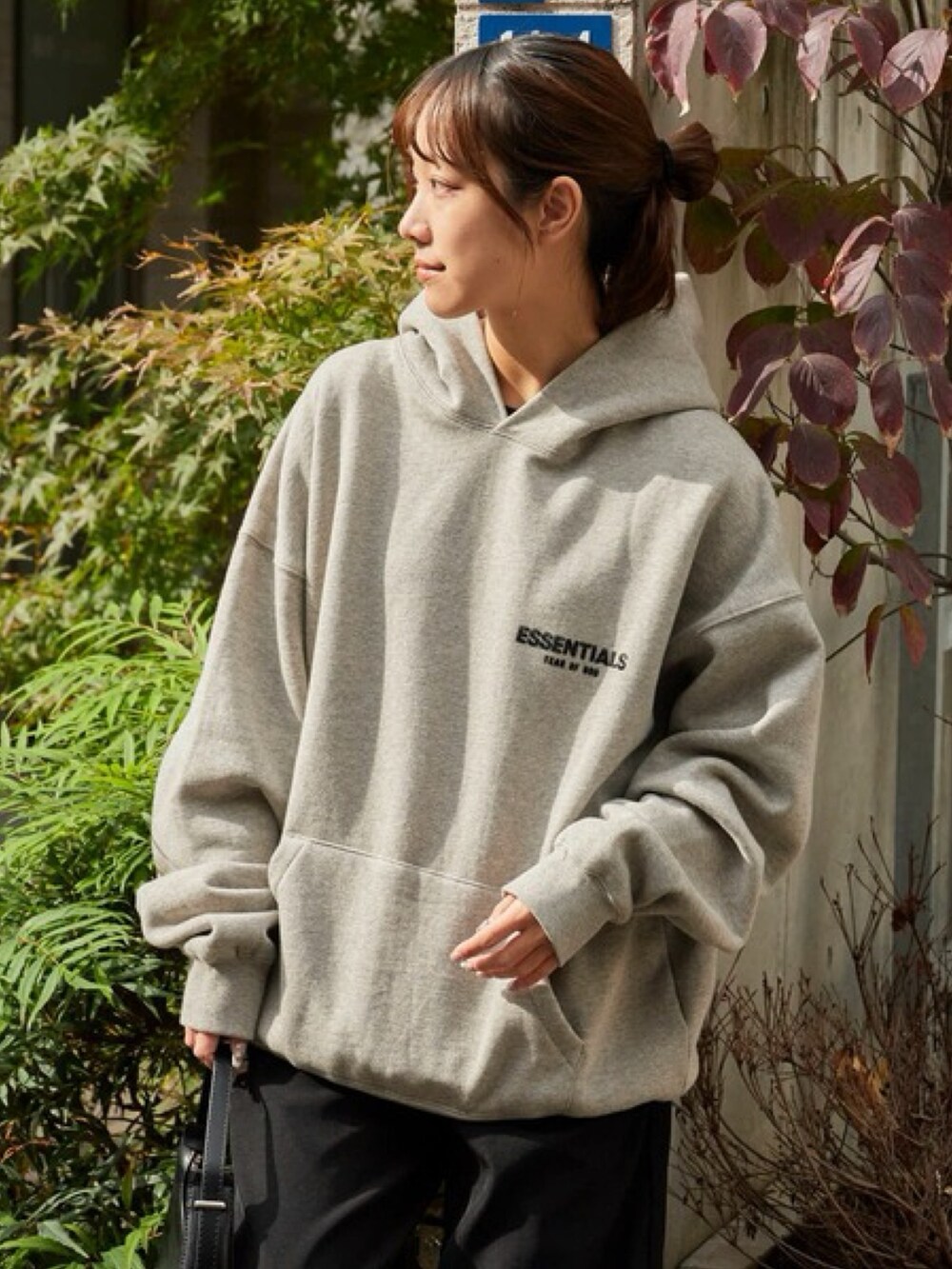 グレー系のパーカー、ブラック系のスラックス、レッド系のスニーカーを着用したレディースの秋コーディネートの4枚目の写真