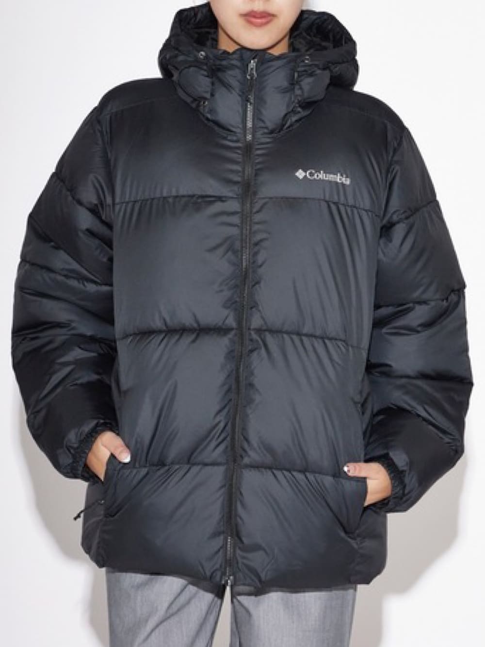 ブラック系のダウンジャケット/コート、グレー系のスラックス、ブラック系のメガネを着用したレディースの秋コーディネートの2枚目の写真