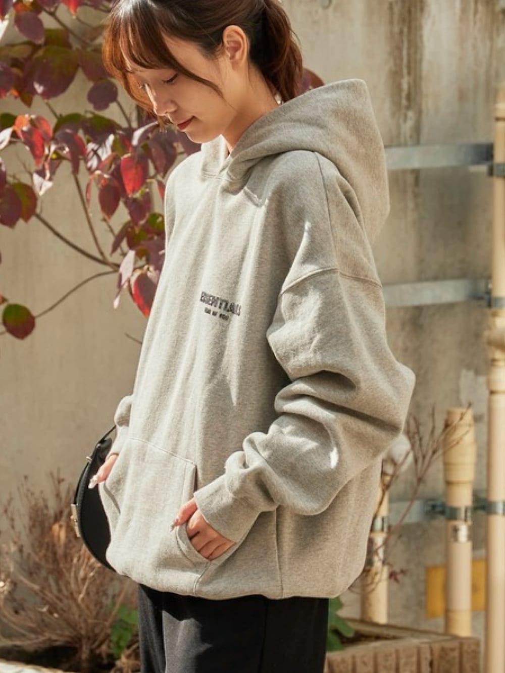 グレー系のパーカー、ブラック系のスラックス、レッド系のスニーカーを着用したレディースの秋コーディネートの2枚目の写真