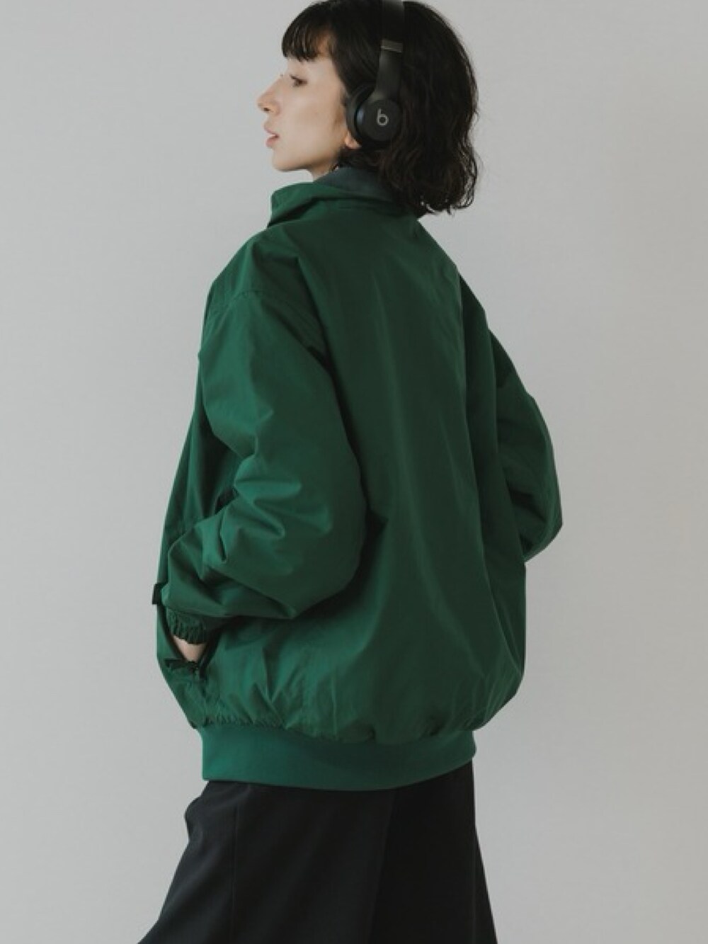 グリーン系のブルゾン、ブラック系のスウェットパンツ、ホワイト系のスニーカーを着用したレディースの秋コーディネートの3枚目の写真