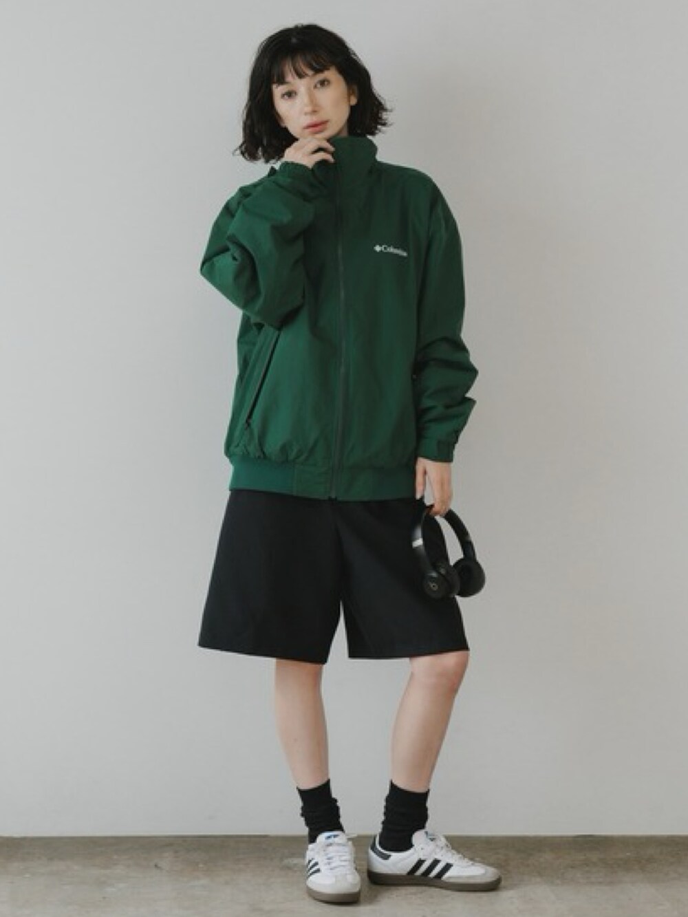 グリーン系のブルゾン、ブラック系のスウェットパンツ、ホワイト系のスニーカーを着用したレディースの秋コーディネートの2枚目の写真