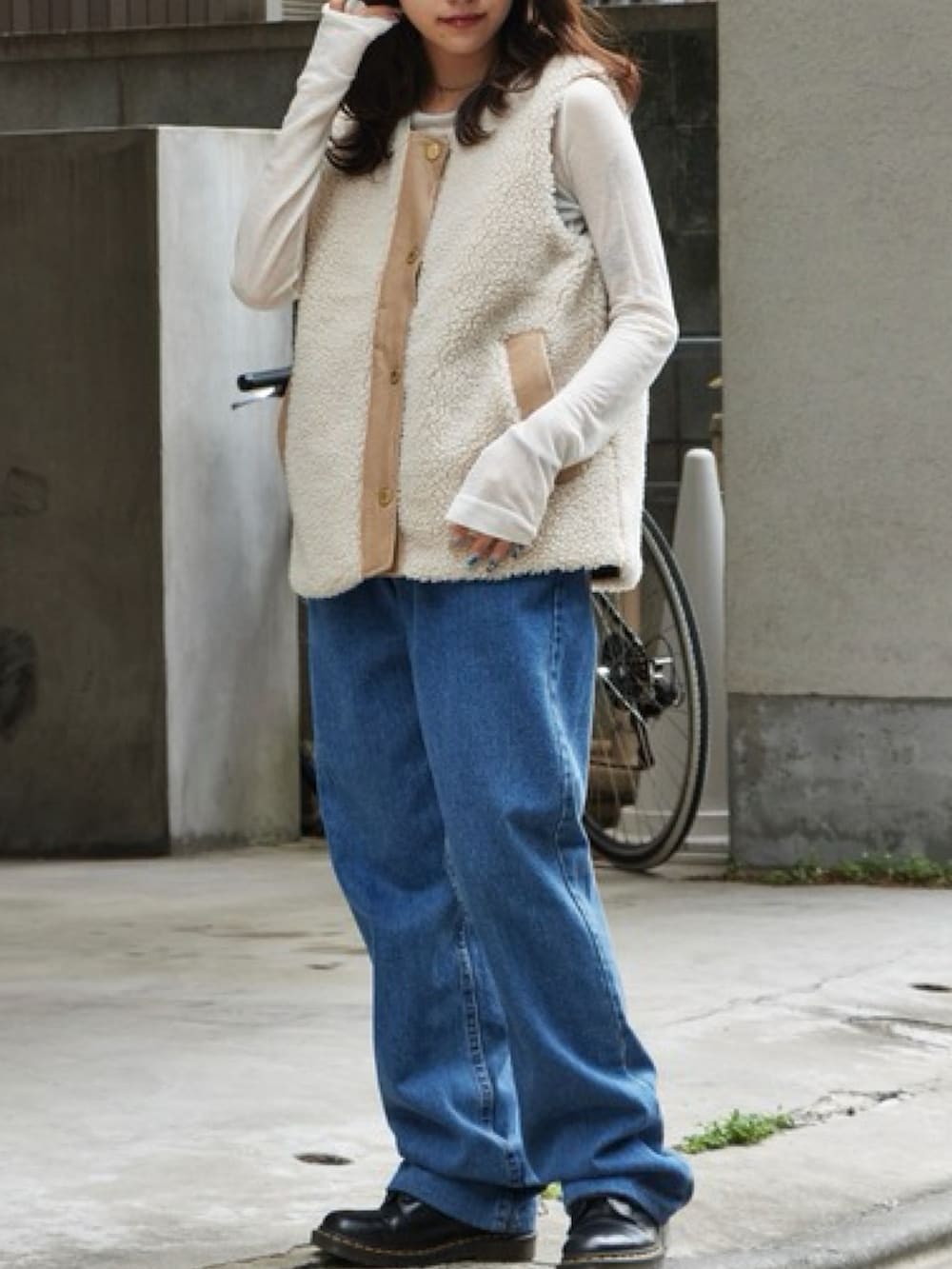 ベージュ系のベスト、ブルー系のデニムパンツ、ブラック系のブーツを着用したレディースの秋コーディネートの2枚目の写真