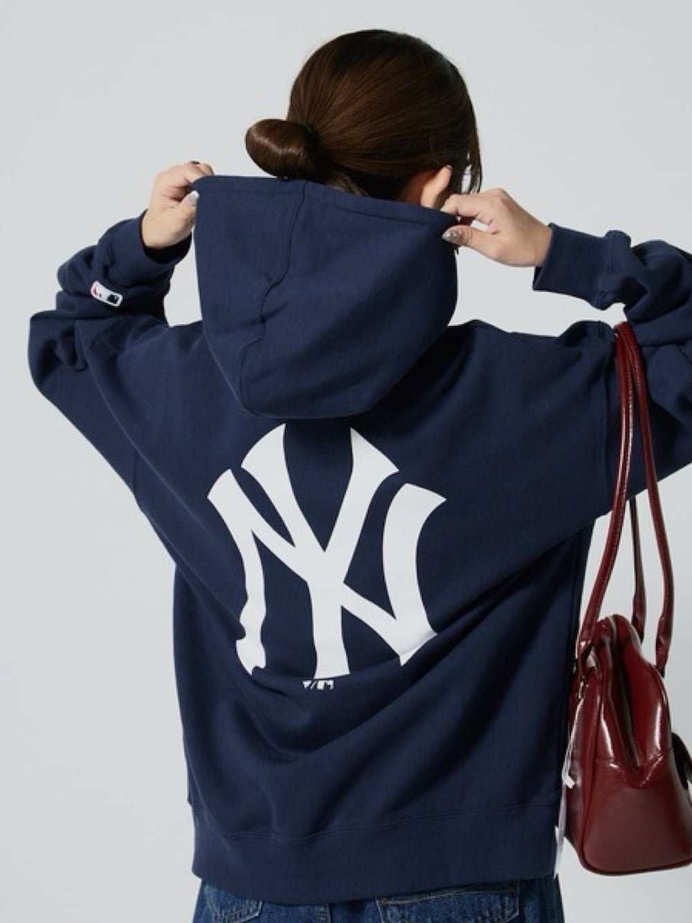 ブルー系のパーカー、ブルー系のデニムパンツ、レッド系のショルダーバッグを着用したレディースの秋コーディネートの3枚目の写真