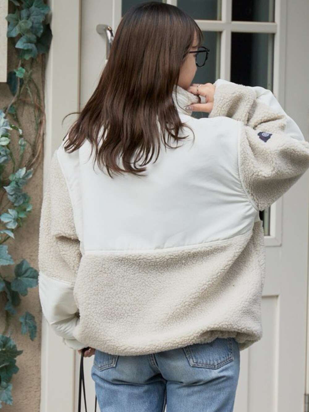 ホワイト系のブルゾン、ブルー系のデニムパンツ、ブラック系のメガネを着用したレディースの秋コーディネートの3枚目の写真